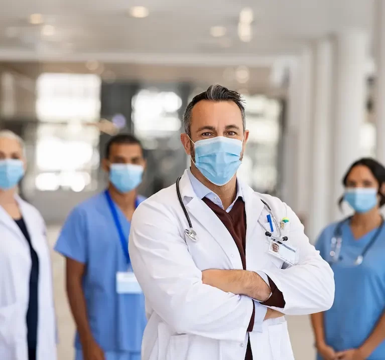 A locum tenens doctor standing and crossing his arms with other healthcare professionals