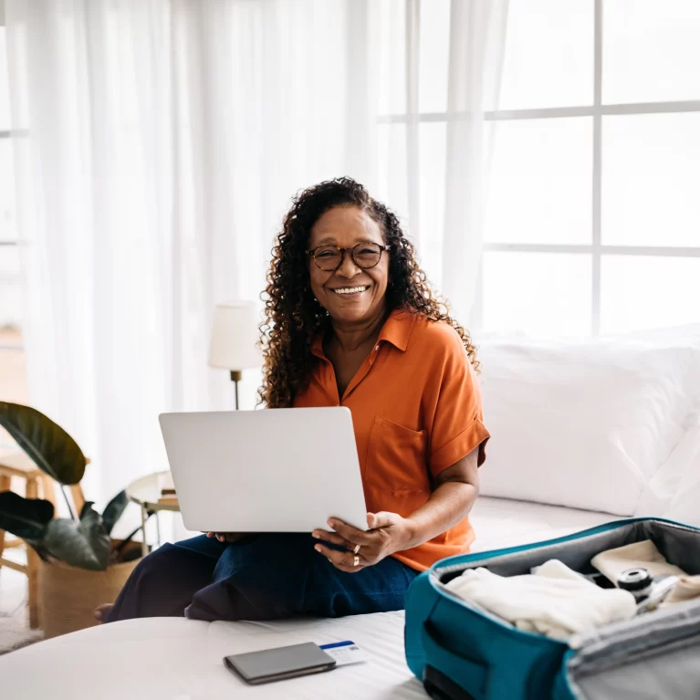 Future Locum Tenens professional locating accommodations for their contract on their laptop while sitting next to a suitcase