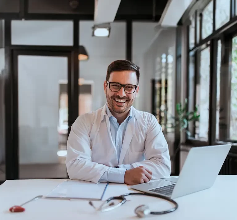 Locum Tenens physical smiling while working on his laptop in an office