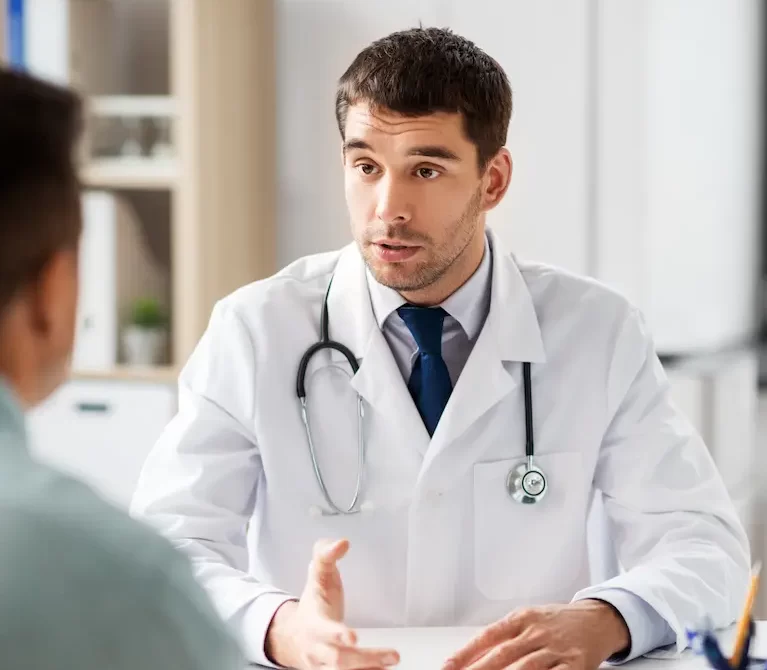 Locum tenens physician talking to a patient while sitting at a desk in a doctor's office