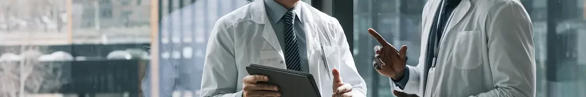 Two locum tenens physicians talking in front of a window while holding a tablet
