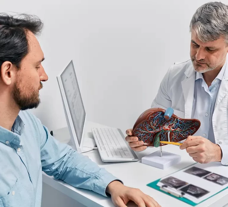 Locum gastroenterologist sitting at a desk with a patient with a diagram of the stomach