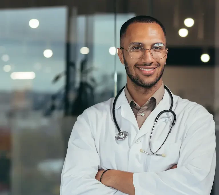 Young Millennial locum tenens physician smiling and crossing his arms