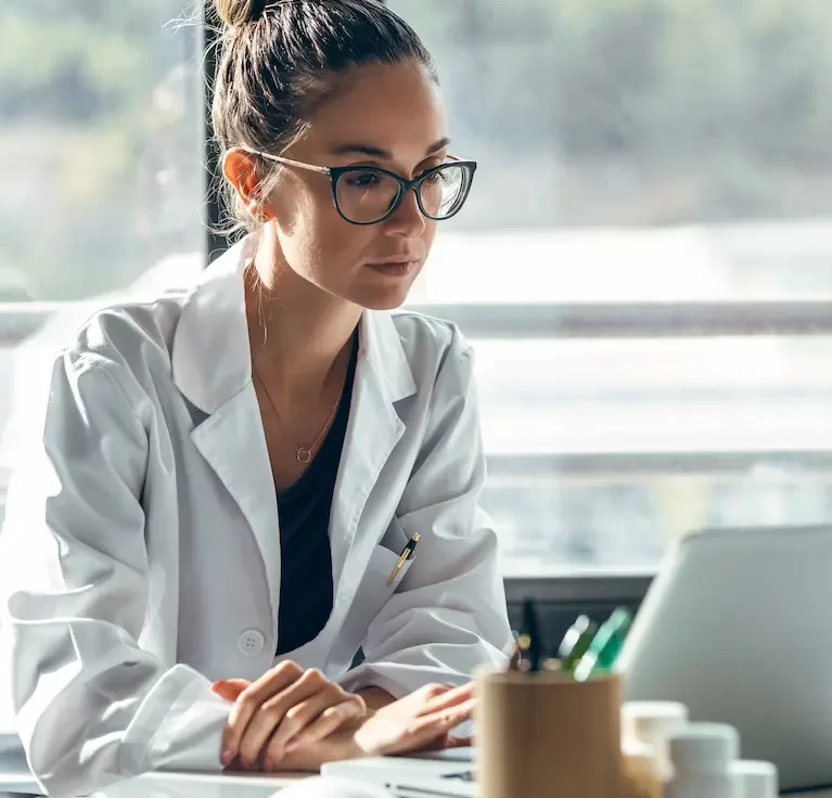 Locum tenens professional sitting at a desk on a laptop looking over compensation packages