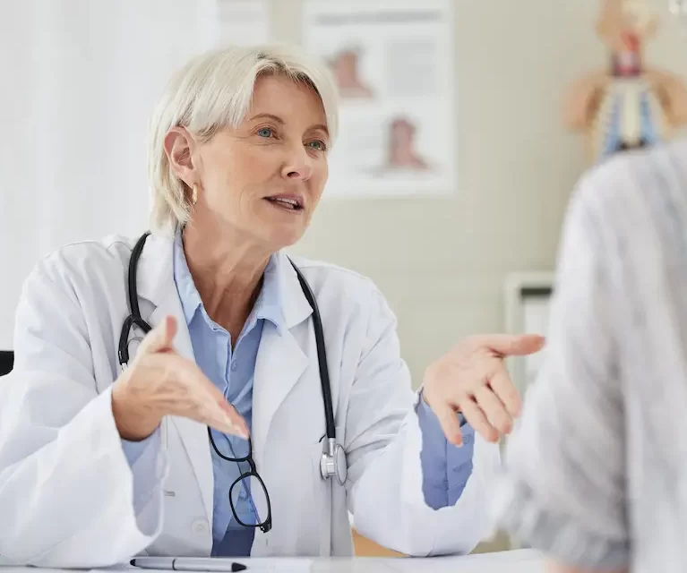 Locum tenens professional speaking to a patient while sitting at a desk at a doctor's office